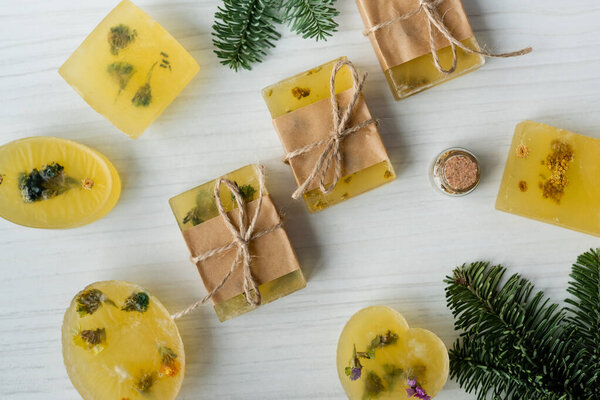 Top view of handmade soap bars near pine branches on table 