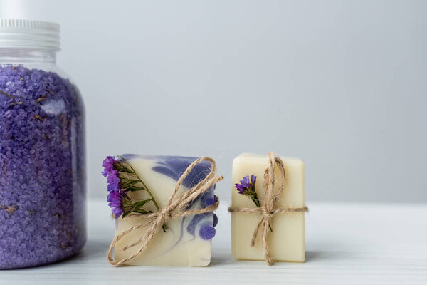 Закрыть вид на морскую соль возле мыла ручной работы с цветами на сером фоне 