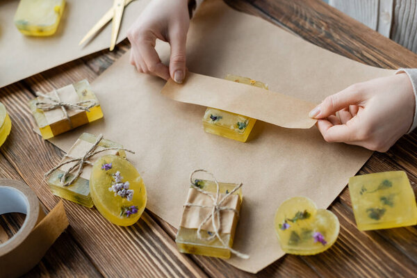 high angle view of craftswoman packaging handmade soap with dry flowers at home 