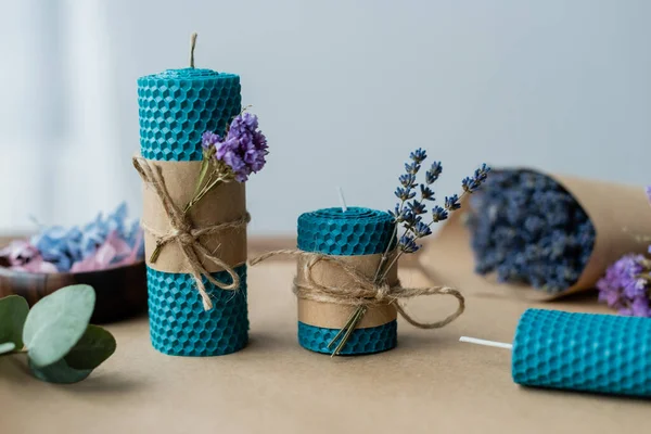 Handmade candles with lavender flowers on craft paper on grey background