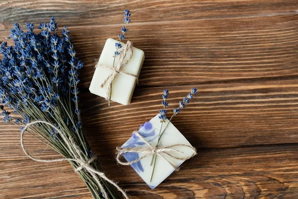 Top view of lavender flowers near handmade soap on wooden surface 
