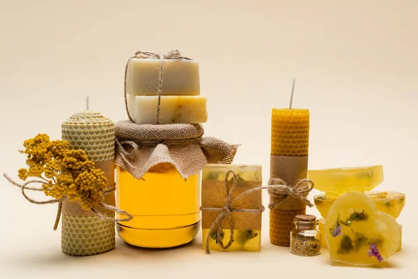 Handmade soap, candles and jar with honey on beige background