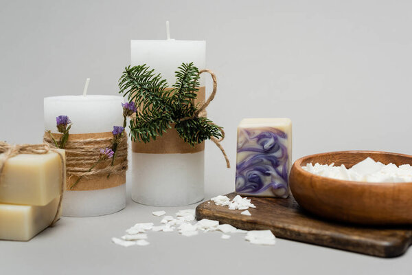 Craft soap near candles with plants on cutting board on grey background 