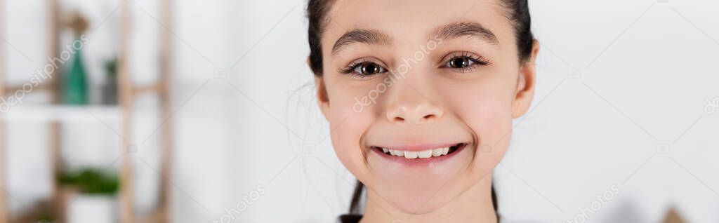 portrait of cheerful girl smiling at camera at home, banner