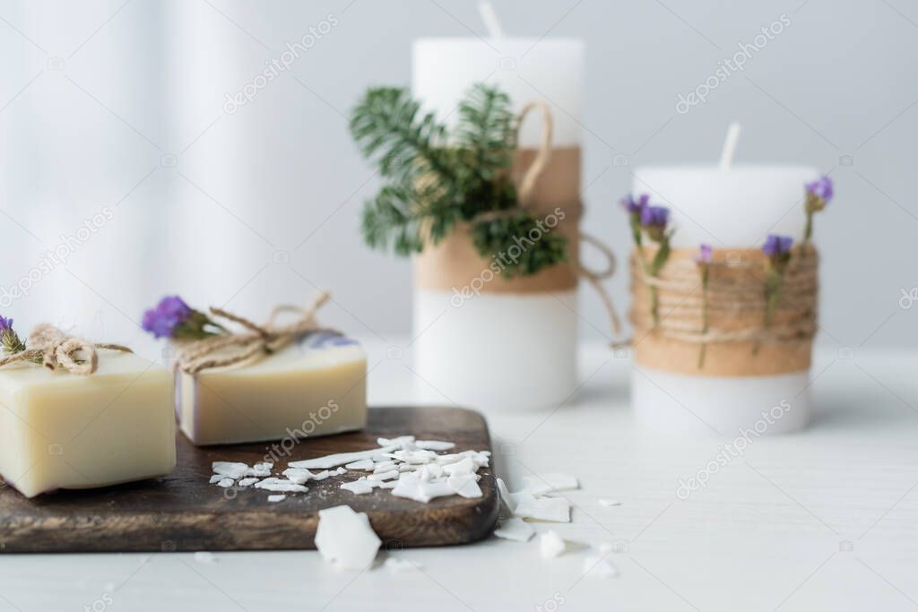Craft soap on cutting board near blurred candles on table 