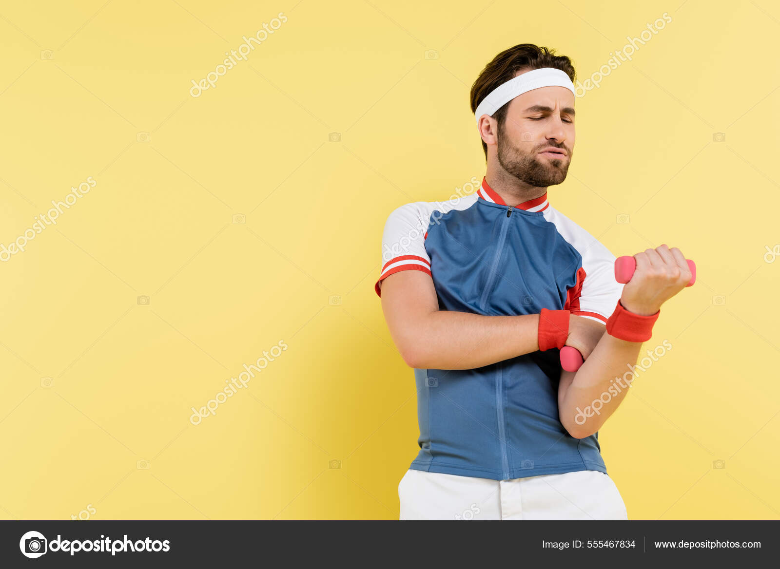 Tensed Sportsman Working Out Dumbbells Isolated Yellow Stock Photo by