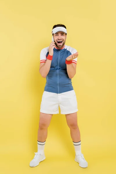 Full Length Excited Sportsman Talking Smartphone Looking Camera Yellow Background — Stok Foto