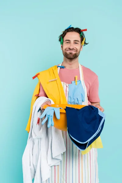 Glimlachende Man Wasknijpers Met Waskom Met Kleren Geïsoleerd Blauw — Stockfoto