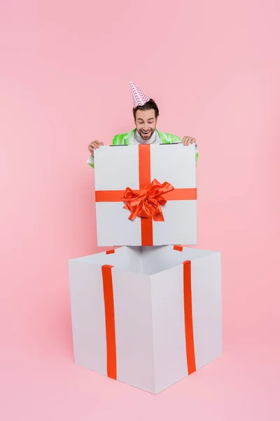 Eccitato Uomo Berretto Partito Guardando Enorme Scatola Regalo Sfondo Rosa — Foto Stock