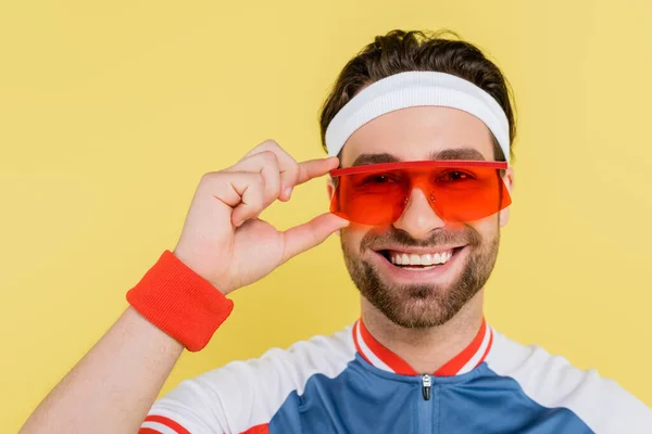Szczęśliwy Sportowiec Trzymający Okulary Przeciwsłoneczne Patrzący Kamerę Odizolowaną Żółto — Zdjęcie stockowe