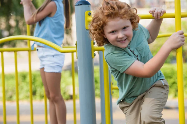 Aufgeregter Junge Schaut Kamera Während Auf Spielplatz Nahe Der Verschwommenen — Stockfoto