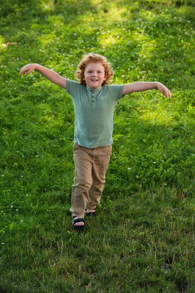 Full Length View Happy Boy Outstretched Hands Walking Green Lawn — Stock Photo, Image