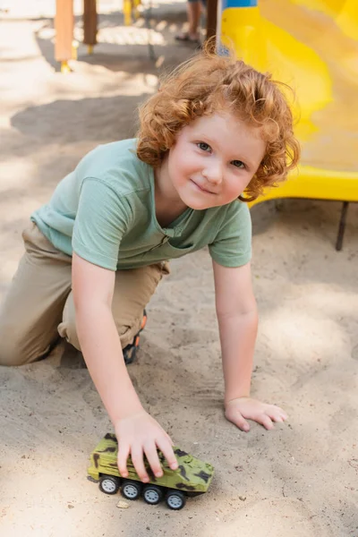 Curly Boy Looking Camera While Playing Sand Toy Armored Vehicle — Stock Photo, Image