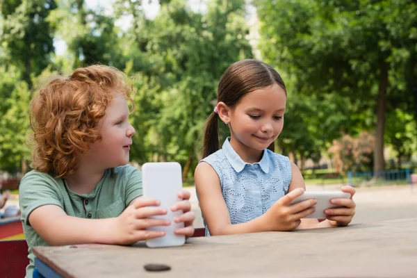 Ragazzo Ragazza Positiva Utilizzando Smartphone Mentre Seduto Nel Parco — Foto Stock