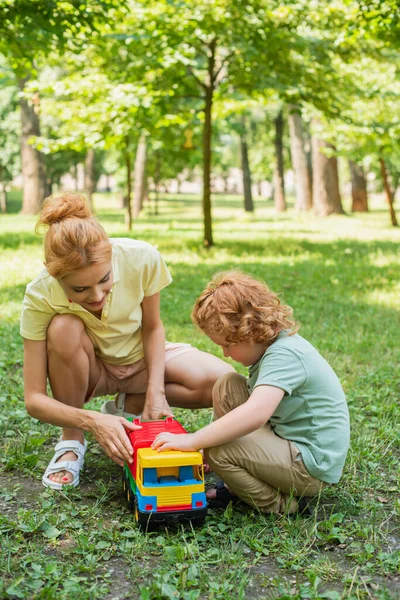 Ruiva Mãe Filho Brincando Com Caminhão Brinquedo Gramado Verde Parque — Fotografia de Stock