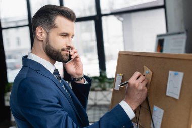 Akıllı telefonda konuşurken tıpa üzerindeki yapışkan nota gülümseyen ekonomist