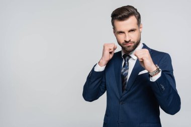 Gri renkli kameraya bakan yumruklarını sıkmış ciddi bir iş adamı.