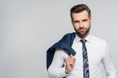 Beyaz gömlekli iş adamı spor ceket giyiyor ve gri renkli kameraya bakıyor.