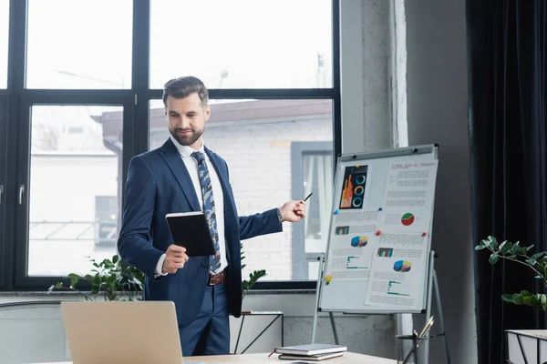 Smiling Economist Notebook Pointing Flip Chart Graphs Online Conference — Stock Photo, Image