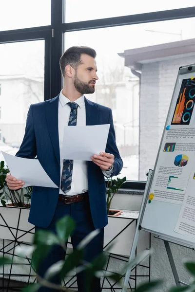 Economista Com Papéis Que Olham Para Análise Flip Chart Escritório — Fotografia de Stock