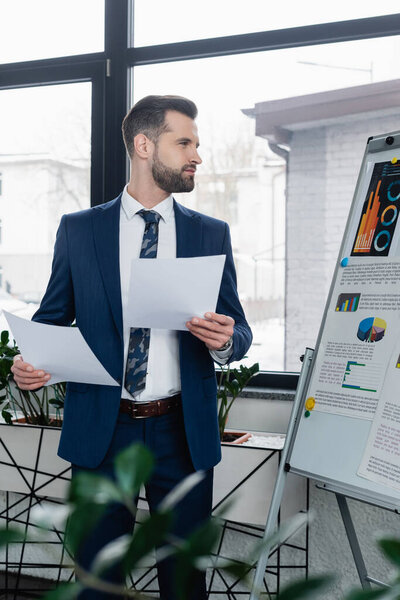 economist with papers looking at analytics on flip chart in office
