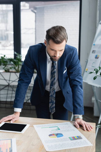 brunette economist looking at analytics near digital tablet with blank screen