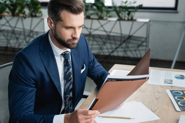 Economist Looking Folder While Working Blurred Graphs Desk — стоковое фото