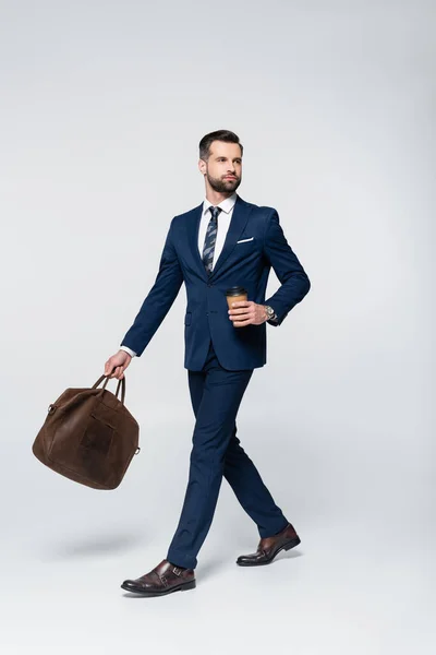 ブルースーツに身を包んだ経済学者がコーヒーを片手にグレーの革のブリーフケースを持って — ストック写真