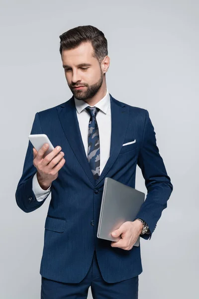 Brunette Businessman Laptop Looking Mobile Phone Isolated Grey — стоковое фото