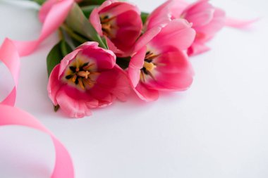Beyaz kurdelenin yanında pembe lale demeti