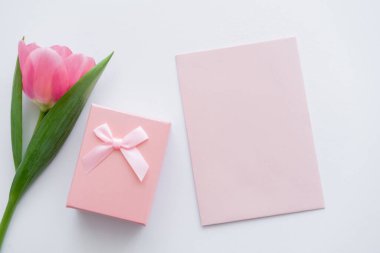 top view of envelope near gift box and pink tulip on white  clipart