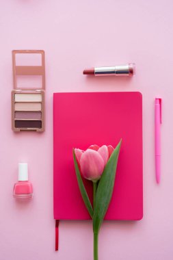 Not defterindeki lale, pembe üzerindeki kalem ve dekoratif kozmetik.