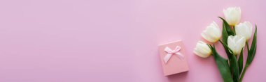 Pembe pankartta hediye kutusunun yanındaki beyaz lalelerin üst görüntüsü