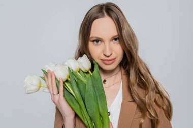 Gri renkli kameraya bakan beyaz laleli güzel kadın.
