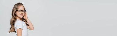 Gri pankartta izole edilmiş, uzun saçlı, gözlüklü neşeli bir kız.