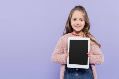 Mor üzerine izole edilmiş boş ekranlı dijital tablet tutan mutlu kız