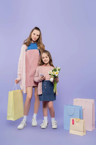全身上下都拿着花 用智能手机和妈妈站在紫色购物袋边 — 图库照片