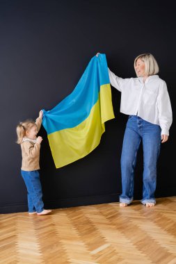Kara Duvar 'ın yanında Ukrayna bayrağı taşıyan heyecanlı anne ve kızın geniş açılı görüntüsü