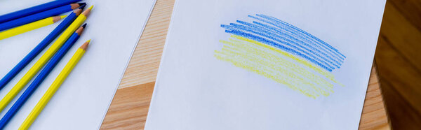 верхний вид цветных карандашей возле белой бумаги с синими и желтыми штрихами, баннер