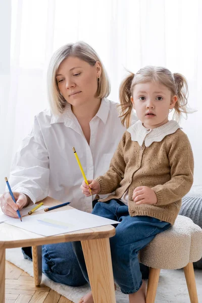 Chica Con Coletas Sosteniendo Lápiz Amarillo Mirando Cámara Cerca Madre — Foto de Stock