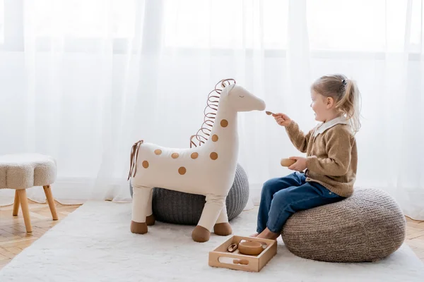 在家里玩纸袋时 女孩用木碗喂玩具马的全景 — 图库照片