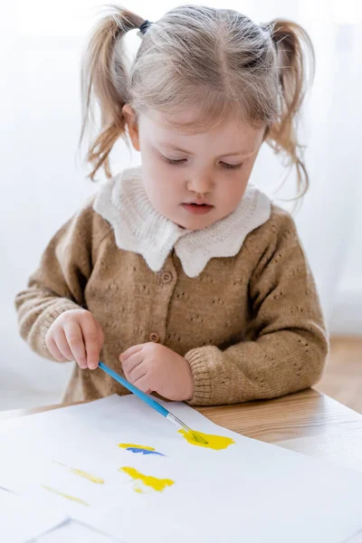 一个小女孩 她的马尾画着蓝色和黄色的画 — 图库照片