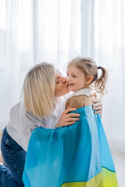 Blondynka Kobieta Całuje Wesoły Córka Pokryte Ukraiński Flaga — Zdjęcie stockowe