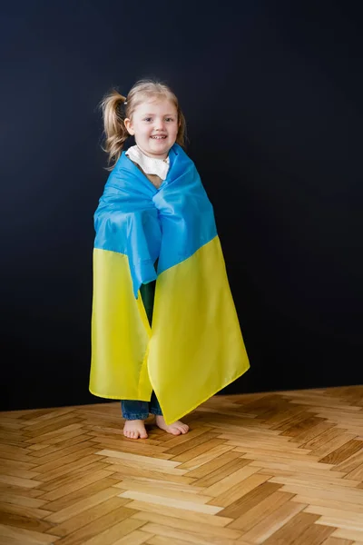 Полный Вид Босиком Девушки Покрытой Украинским Флагом Стоящей Черной Стены — стоковое фото