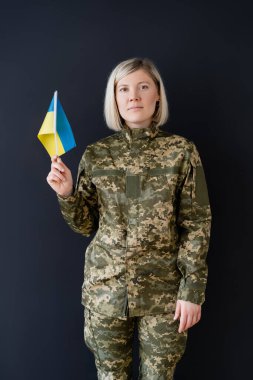 front view of military woman with ukrainian flag looking at camera isolated on black clipart