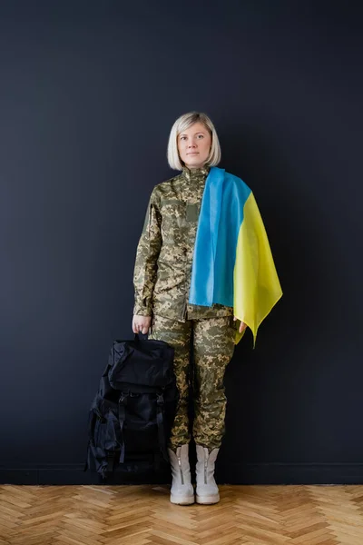 Полная Длина Военной Женщины Украинским Флагом Рюкзаком Возле Черной Стены — стоковое фото