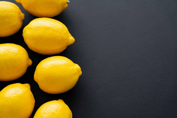 Top view of bright lemons on black background with copy space