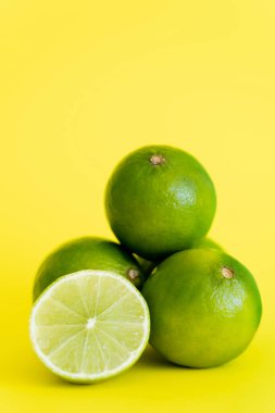Close up view of half and limes on yellow background 
