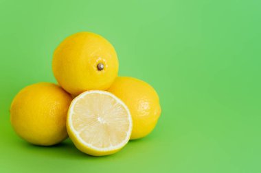 Half of juicy lemon on green surface with copy space