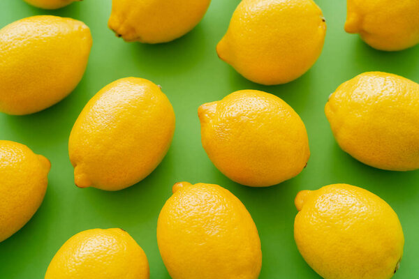 Top view of bright fresh lemons on green background